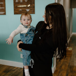 Haley McCaskill, COO of Revive Infusions & Wellness in Roseburg, Oregon, holding her toddler daughter, providing guidance on weight loss, nutrition, and wellness programs for patients in Douglas County.