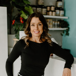 Chenelle McCaskill, PA-C and owner of Revive Infusions & Wellness, standing at the front desk reception on Garden Valley Blvd in Roseburg, Oregon, welcoming new patients for women’s health, men’s health, and wellness services.