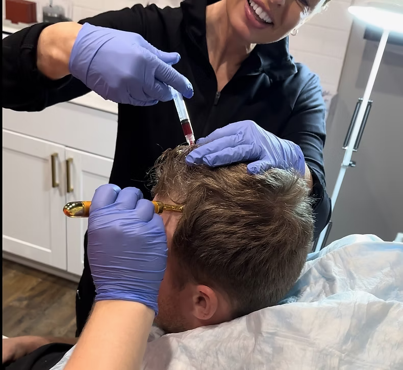 Chenelle-applying-PRF_PRF EZ Gel Revive-hair-restoration Medical Primary Care Provider, Chenelle McCaskill applying PRP to scalp of a male patient for hair restoration in a private medical exam room with the help of a medical assistant.