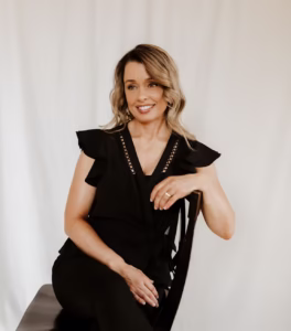Founder, PA-C, MS, Medical Provider Chenelle McKaskill is pictured in a refined headshot, seated on a black wooden chair against a clean white backdrop. Dressed in an elegant all-black ensemble with her hair worn down in soft curls, this portrait reflects the elevated, patient-centered care offered at our Roseburg, Oregon medical spa. As a leader in functional primary care, same-day rapid care, PRP and PRF treatments, hair restoration, advanced skin aesthetics, IV nutrient therapy, and red light therapy, Chenelle McKaskill delivers personalized, results-driven medical and wellness services designed to optimize health, longevity, and confidence.